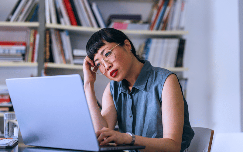 A modern woman thinking while looking at her work laptop